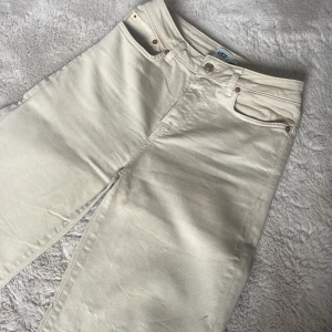 Ljusbeige jeans med rå kant - Snygga ljusbeige jeans med raka ben och rå, fransad kant nertill. Klassisk femficksmodell med knapp och dragkedja framtill. .