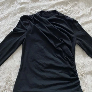 Svart omlottopp från SHEIN - Snygg svart omlottopp från SHEIN med lång ärm och draperad effekt framtill. Toppen har en stilren look och passar perfekt till jeans eller kjol. Mjuk och skön känsla, lätt att matcha med olika outfits.