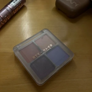 BTY by NA-KD ögonskuggspalett 4 färger - Säljer en fyrkantig ögonskuggspalett från BTY by NA-KD med fyra nyanser: rosa, rosé, violett och mauve. Paletten är kompakt med transparent lock. Färgerna är både matta och skimrande, perfekt för kreativa looks. 