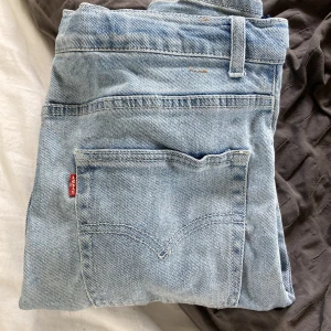 Levi's 551Z ljusblå raka jeans - Ljusblå Levi's 551Z Authentic Straight jeans med klassisk femficksdesign och rakt ben. Jeansen har dragkedjegylf, Levi's röda etikett på bakfickan och är tillverkade i slitstarkt bomullsjeans. Perfekta för en avslappnad och tidlös stil.