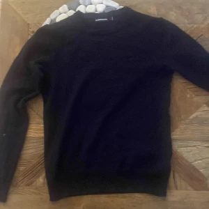 Mörkblå stickad tröja från J.Lindeberg - En snygg mörkblå stickad tröja från J.Lindeberg i storlek S. Den sitter dock som en Xs då den har krympt i tvätten , annars jätte bra skick
