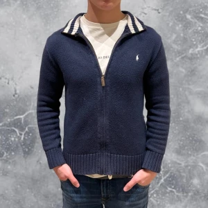 Ralph Lauren Zip tröja blå - •Ralph Lauren Full-Zip kofta Navy Blå. Skick: 8/10, Inga skador! Storlek: 14/16 år = XS~. •Mått, axel-neråt: 55 cm, bredd: 45 cm. Modell: 173 cm, 63 kg. Authentic: ✅. Hör av dig vid frågor eller funderingar, Mvh Liam