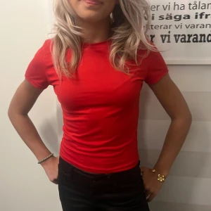 Röd tight t-shirt i bomull - Enkel och stilren röd t-shirt med tight passform och korta ärmar. Gjord i mjuk bomull som sitter snyggt mot kroppen. Perfekt till jeans eller shorts för en clean look.