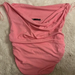 Rosa blus/topp från Zara - Supersöt rosa kort blus/topp från Zara med draperad halsringning och rynkade sidor. Klänningen har ärmlös design och smala axelband, perfekt för en trendig look. Tillverkad i mjukt material som känns skönt mot huden.🩷