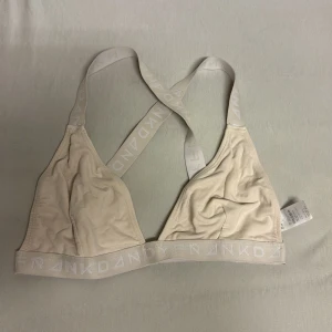 Beige topp från Frank Dandy - Snygg beige bh-topp från Frank Dandy med brottarrygg och breda resårband med logga. Tillverkad i mjuk tencel och elastan för en skön passform. Perfekt för en chill och sportig look. 
