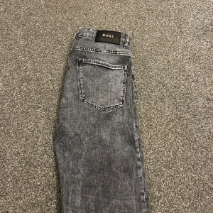 Grå jeans från BOSS - Snygga grå jeans från BOSS. Jeansen har en metallogo vid myntfickan. Perfekta för dig som gillar stilrena och trendiga jeans.