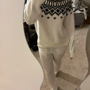 Vit stickad tröja med mönster från hm - Supermysig vit stickad tröja från hm med svart och grått grafiskt mönster upptill. Tröjan har lång ärm, ribbade muddar och en klassisk rund hals. Perfekt för kalla dagar och snygg till både jeans och kjol.