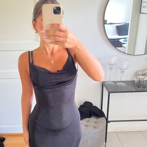 Svart långklänning med öppen rygg - Supersnygg svart långklänning med smala axelband och draperad urringning. Klänningen har en tight passform och öppen rygg med knyt i ryggen. Perfekt för dig som vill sticka ut och känna dig extra glam. Passar dig som har storlek 34 & 36!