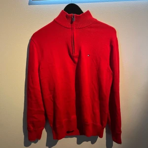 Röd Tommy Hilfiger half zip  - Aldrig använd snygg röd half zip från Tommy Hilfiger med krage. Storlek L men passar M mer. Aldrig använd då den köptes ny men för liten för mig. Ny pris 1699. Priset kan budas.