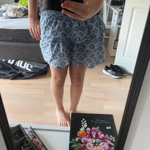 Blåmönstrad kjol från Ginatricot - Säljer ett par blå och vit kjol från Ginatricot med snyggt rutigt mönster och elastisk midja. De är loose fit och perfekta för varma sommardagar. Lätta och sköna i bomullsmaterial, passar dig som gillar avslappnad stil.