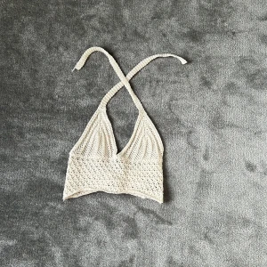 Vit virkad halterneck topp Romwe - Superfin vit virkad halterneck topp från Romwe i storlek XXS. Toppen har knytband i nacken och snörning i ryggen för perfekt passform. Den är croppad och har en snygg boho-vibe, perfekt till sommaren och festivaler.