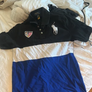 Pikétröja Polo Ralph Lauren svart/blå - Snygg pikétröja från Polo Ralph Lauren i svart, vitt och blått.  Använd fåtal gånger förra året.