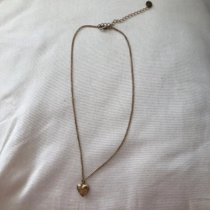 Guldigt halsband med hjärta äkta guld! - Superfint halsband i guld med hjärtformat belockhänge. Berlocken har ingraverade blommor och hjärtan och går att öppna för att lägga in en liten bild om man vill. Fick den i present för föera år sedan men inte använd.  äkta guld