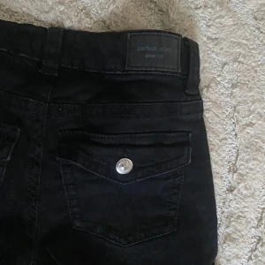 Svarta lågmidjade bootcut jeans från Gina Tricot - Säljer ett par svarta lowwaist bootcut jeans från Gina Tricot. De har låg midja, klassiska fickor med lock och knappdetalj bak samt snyggt utsvängda ben. Perfekta till sneakers eller boots och sitter riktigt snyggt på. inte mycket andvända då de är lite korta för mig 💕💕