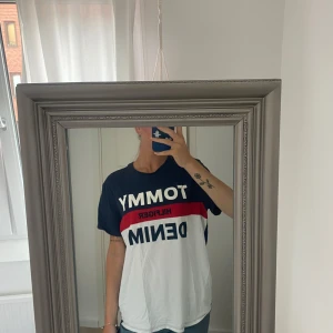 Tommy Hilfiger Denim t-shirt i färgblock - Snygg t-shirt från Tommy Hilfiger Denim med stora logotryck framtill. T-shirten har färgblock i marinblått, rött och vitt, klassisk rund hals och korta ärmar. Tillverkad i mjuk bomull och har en relaxed fit som ger en chill vibe.