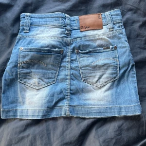 Blå jeanskjol från G-Star RAW - Snygg blå jeanskjol från G-Star RAW med klassisk femficksdesign, bälteshällor och slitna detaljer. Storlek 26. Säljer pga att jag inte använder längre! 