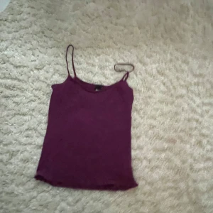 Mörklila linnetopp med smala axelband - Säljer en enkel och stilren mörklila linnetopp med tunna axelband. Toppen har en rak passform och är perfekt för varma dagar eller som lager under en skjorta. Färgen är djup och snygg, och modellen är klassisk och lätt att matcha.
