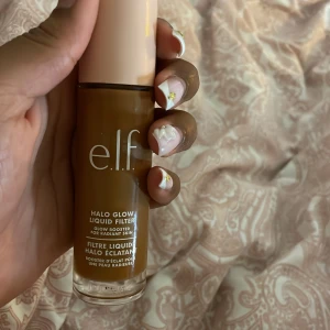 e.l.f. Halo Glow Liquid Filter - Glow booster från e.l.f. i flytande form, Halo Glow Liquid Filter. Ger en skinande och fräsch finish med mjuk lyster. Innehåller squalane och hyaluronsyra. Kommer i en glasflaska med beige lock, 31,5 ml. Perfekt för att skapa glow-effekt.