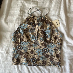 Blommig topp - Superfin blommig topp från märket BikBok💕Toppen har aldrig blivit använd och har prislappen kvar. Banden korsas i ryggen och är justerbara. Nypris 199kr☺️