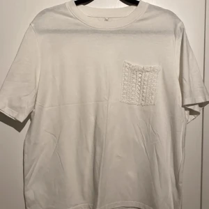 Vit t-shirt med spetsficka! -  Nyskick Är endast använd vid ett tillfälle!  Jättefint skick!  Rak modell