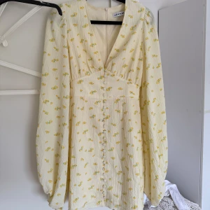 Gulblommig adoore klänning - Jättefin kort klänning från Adoore i ljusgul nyans med små gula blommor. Klänningen har v-ringning, långa puffärmar och knappar framtill. Den är i storlek 32, och endast använd en gång. Säljer pågrund av att jag har en till💕💕Pris kan diskuteras!