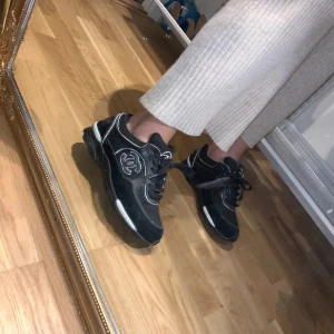 Svarta sneakers med logga - Snygga svarta sneakers med tydlig vit logga på. Notera att inne vart hällen är, är det slitet, därav priset.