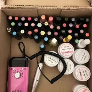 Stort kit med nagellack och gel, förklädde, mask, etc  - Säljer ett komplett nagelkit med massor av färgglada gel- och nagellack, flera burkar extension nail gel, nagelolja och elfil i metallicrosa. Perfekt för dig som älskar att fixa naglarna hemma! Färgerna varierar från nude till starka nyanser.
