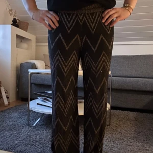 Svarta byxor med glittrigt missoni liknande mönster - Snygga svarta byxor med glittrigt missoni liknande mönster i. Byxorna har en rak och lite loose passform med resår i midjan