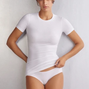 Vit intimissimi t shirt - Säljer en klassisk vit t-shirt med tight passform och rund hals. T-shirten har korta ärmar och är gjord i mjuk bomull som sitter skönt mot kroppen. Perfekt för en clean och enkel stil.