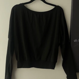 Svart långärmad tröja med bred hals - Off shoulder tröja med handvärmare. 