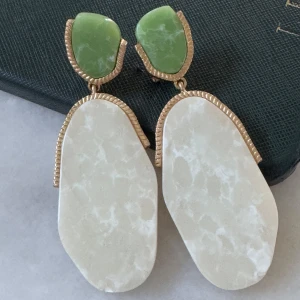 Statementörhängen med grön och vit sten - Stora örhängen med en cool kombination av grön och vit sten, inramade av guldfärgade detaljer. De har en organisk, oregelbunden form som ger en unik vibe och sticker ut. Perfekta för dig som vill ha något annorlunda och trendigt.