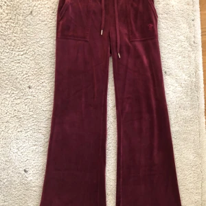 Vinröda velourbyxor med snörning, juicy couture - Vinröda juicy couture byxor i storlek S. Hyfsat bra skick, finns ett litet brännmärke men det är inget som är tydligt och syns. 