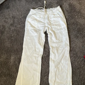 Vita linnebyxor från Roxy - Snygga vita linnebyxor från Roxy med avslappnad passform och dragsko i midjan. Byxorna har bred resår och praktiska fickor framtill. Perfekta för en chill och somrig look.