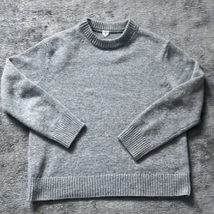 Grå stickad tröja med rund hals - Säljer en enkel och stilren grå stickad tröja från det stilrena märket ARKET med rund halsringning. Tröjan har ribbade muddar vid ärmslut och nederkant, perfekt för lager på lager under kyliga dagar. Passar dig som gillar en clean och klassisk look. Den är i storlek XS men sitter mer som en S/M. Kom gärna med bud!!! Allt gott 