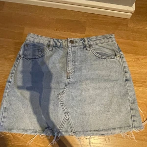 Ljusblå jeanskjol från BDG - Säljer en ljusblå jeanskjol från BDG (Urban Outfitters) i klassisk denim, fransiga kanter nertill. Fickor fram och bak. 