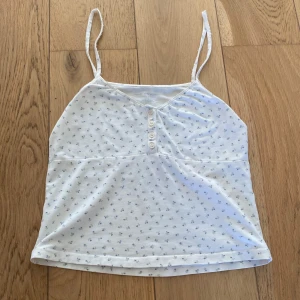 vitt blommigt linne från Brandy Melville - ord. pris: 200kr.  sött vitt linne med blått blommigt mönster från brandy melville 🫐🤍🫶🏻💙 säljer därav att den inte kommit till användning på några år