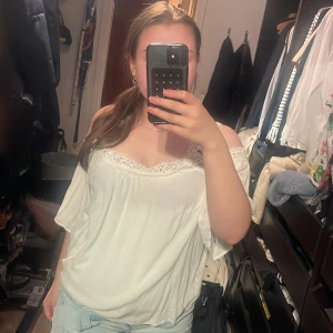 Vit offshoulder blus med spets från Pull&Bear - Säljer en vit offshoulder blus från Pull&Bear med fina spetsdetaljer längs halsringningen. Blusen har en lös passform och är tillverkad i ett mjukt, lätt material. Perfekt för sommaren om man vill se lite söt ut och inte ha på sig något varmt❤️❤️❤️