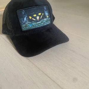 Svart aik keps all size - Säljer en stilren svart aik keps, all size då man kan justera storleken enkelt bak på kepsen. Justerbar passform med plastspänne bak. Perfekt accessoar för en sportslig känsla. Kepsen är helt ny, helt oanvänd.