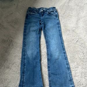 Blå jeansbyxor från Gina Tricot med broderade bakfickor - Säljer ett par klassiska blå jeansbyxor från Gina Tricot med snygga broderade detaljer och nitar på bakfickorna. Byxorna har normal passform och raka ben, perfekt för en avslappnad stil. Ord 400kr