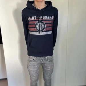 Marinblå hoodie från Saint Laurent - Lägger ut min marinblåa hoodie från Saint Laurent då den inte passar mig, Strl M men passar även S. Skicket är 9 utav 10 då den knappt är använd. Äkthetsbevis finns, skriv om ni har någon fråga!🙌 Lägg gärna bud då pris inte är hugget i 🪨