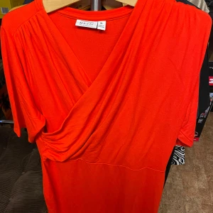 Masai omlottklänning Ny! stl XL - Säljer en röd omlottklänning från Masai i storlek XL. Klänningen har trekvartsärm och en snygg v-ringning framtill. Tillverkad i mjukt och stretchigt material, perfekt för dig som gillar en bekväm och stilren look. Ny och ej använd.