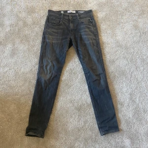 Replay Anbass slim fit jeans i grå tvätt - Säljer ett par Replay Anbass jeans i slim fit med snygg grå tvätt. Klassisk femficksmodell med dragkedjegylf och Replay-logga på fickan. Perfekta för dig som gillar en smalare passform och stilren look.