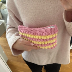 Rosa och gul virkad necessär med dragkedja - Supergullig handvirkad necessär i rosa och gult med vita dragkedja. Perfekt storlek för smink eller annat💓Längden 13 cm och bredden 21 cm💗💗