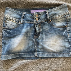 Blå lowaist jeanskjol med dubbla knappar - Säljer denna jätte snygga kjolen då den är förstor, storleken är S/XS. Den har inga defekter! Skriv för fler bilder❤️kjolen är 39 cm tvärsöver, 27 cm i längden.