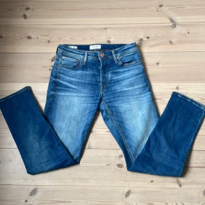 Blå jeans från Jack & Jones - Klassiska blå jeans med en slim passform och raka ben. Jeansen har fem fickor, knappgylf och en snygg tvätt framtill för en avslappnad look. Perfekta till vardags och passar till det mesta i garderoben. Jeansen är i storleken 28/30 men passar snarare längden 32.