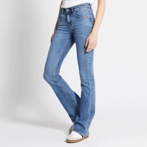 Blå bootcut jeans - Säljer ett par klassiska blå bootcut jeans med hög midja. Jeansen har fem fickor, dragkedja och knapp framtill. Perfekta för dig som gillar en tidlös och avslappnad stil.