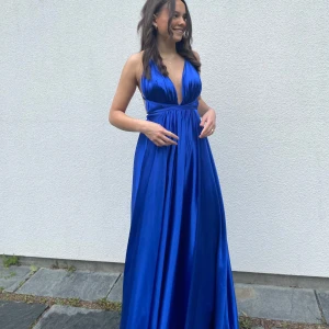 Royal blue balklänning - Säljer en elegant blå långklänning med djup v-ringning och markerad midja. Klänningen har tunna axelband och äkta siden material som ger en lyxig känsla. Perfekt för bal eller festliga tillfällen. Köpt på ivoryfield där nypriset var 3500kr. Andvänt en gång så helt ny.
