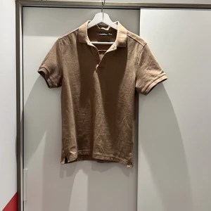 Beige pikétröja från J.Lindeberg - Snygg beige pikétröja från J.Lindeberg (äkta). Nästan helt oanvänd 