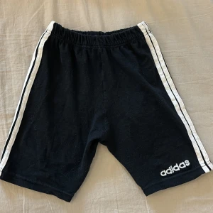 Svarta Adidas shorts - Fina Adidasbyxor i bra kvalite. Har en lagning och lite nopprig på insidan… där av priset, annars inga defekter. Säljs då de är för små för mig. Passar en xs eller xxs!