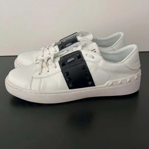 Valentino sneakers - Snygga vita sneakers från Valentino Garavani med svarta detaljer och ikoniska rockstuds. Dom är som nya i skik och passar perfekt till en avslappnad stil. Säljs då dom var för små för mig. LÅDA KOMMER MED.